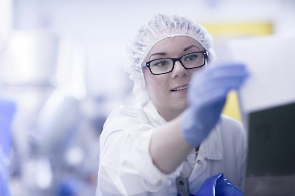 Factory worker wearing hair net looking at paperwork