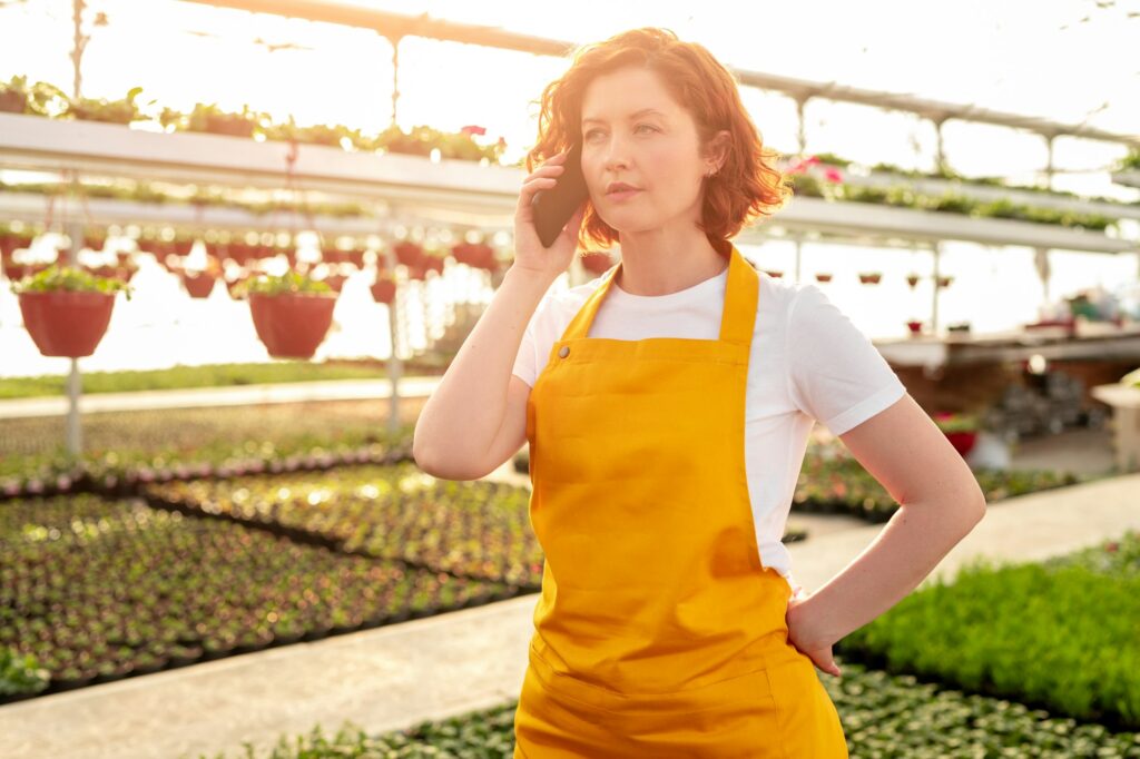 Serious gardener answering call in greenhouse